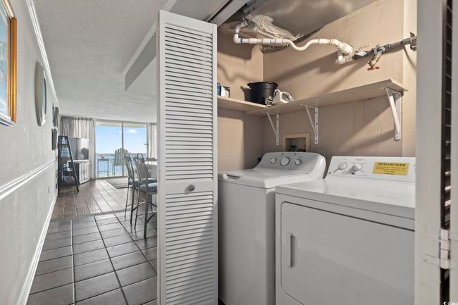 Clothes washing area with a textured ceiling, independent washer and dryer, laundry area, and tile patterned flooring | Image 28