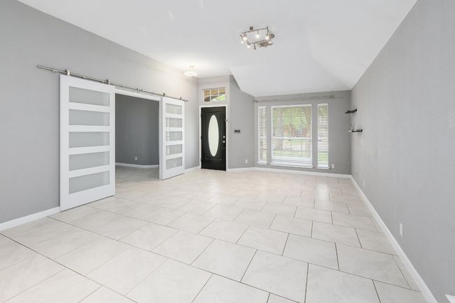 Foyer entrance with a barn door, baseboards, vaulted ceiling, and light tile patterned flooring | Image 17