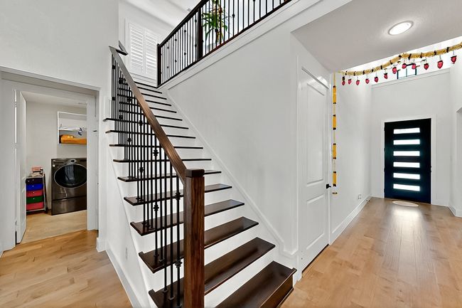Entryway with washer / dryer, wood finished floors, stairs, baseboards, and a towering ceiling | Image 4