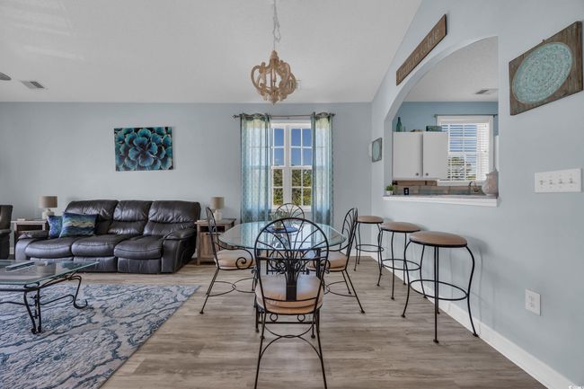 Dining space featuring wood finished floors, visible vents, arched walkways, and a healthy amount of sunlight | Image 13