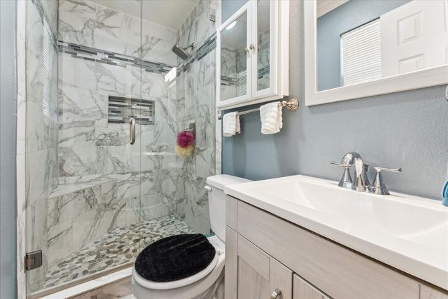 Full bath featuring toilet, a textured wall, and a marble finish shower | Image 9