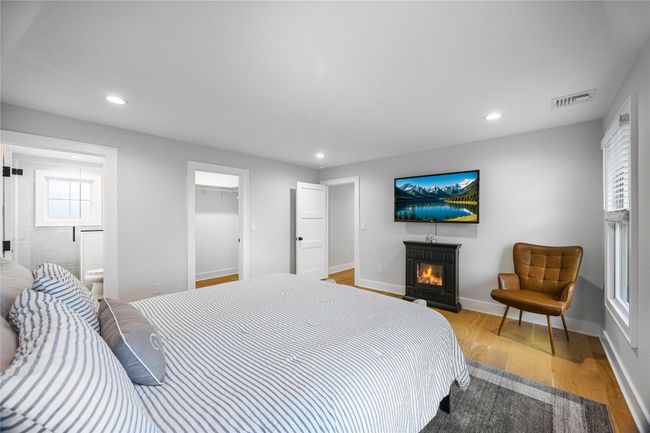 Bedroom with a lit fireplace, baseboards, visible vents, light wood-style floors, and recessed lighting | Image 31