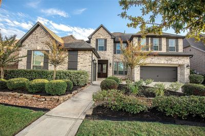 This is a two-story brick home featuring 4 bedroom (2 bedroom down), 4.5 bath, game room and beautiful landscaped front yard, an attached Three-car garage, and a welcoming entrance pathway. | Image 1