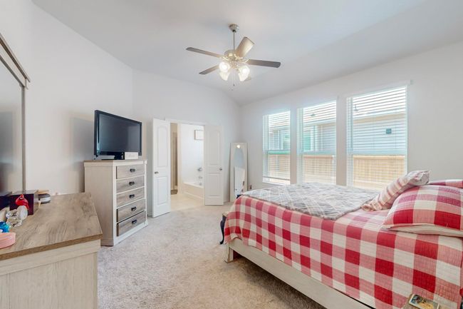 Bedroom with a ceiling fan, connected bathroom, light colored carpet, and vaulted ceiling | Image 12