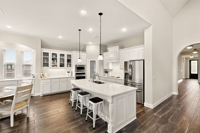 Kitchen featuring stainless steel appliances, a sink, arched walkways, dark wood finished floors, and recessed lighting | Image 8