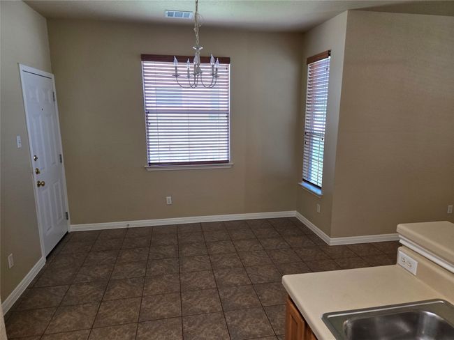 Unfurnished dining area featuring a chandelier and dark tile patterned flooring | Image 11