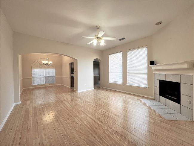 Unfurnished living room with a tile fireplace, ceiling fan, light wood finished floors, and plenty of natural light | Image 5
