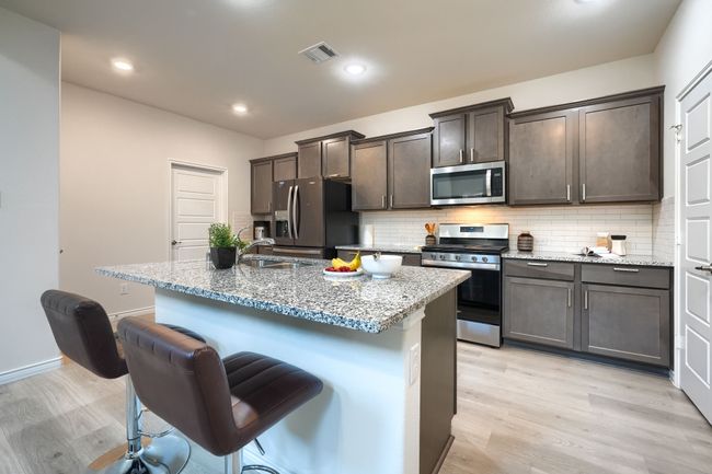 Kitchen with appliances with stainless steel finishes, a sink, light wood-type flooring, light stone countertops, and recessed lighting | Image 10
