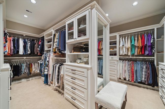 Styled to mimic a high-end Fendi boutique, this masterfully designed 18’ X 15’ walk-in closet is a dream for organization and style, featuring custom built-ins, glass-front cabinetry, and abundant hanging space. Thoughtfully arranged shelves and drawers provide dedicated storage for everything from accessories to seasonal wear, while a full-length mirror add functionality and elegance. A luxurious, boutique-inspired space tailored for daily ease. | Image 29