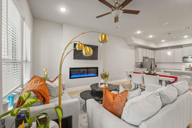 Living area featuring a ceiling fan, a glass covered fireplace, recessed lighting, and light wood-style flooring | Image 4