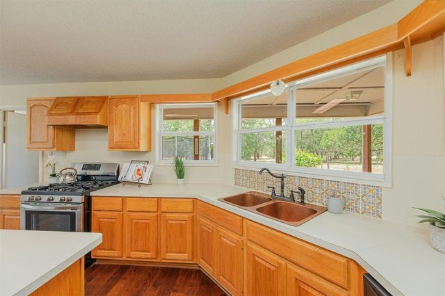 Country kitchen features designer stamped copper sink and gas range. | Image 13
