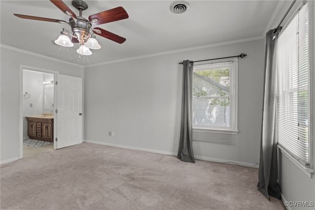 Unfurnished bedroom with a sink, baseboards, visible vents, light colored carpet, and crown molding | Image 20