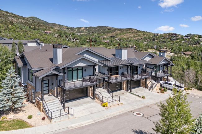 View of front facade featuring a chimney, concrete driveway, an attached garage, stone siding, and roof with shingles | Image 42