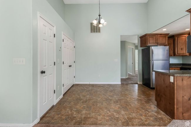 Kitchen with a chandelier, freestanding refrigerator, stone finish floor, baseboards, and visible vents | Image 5