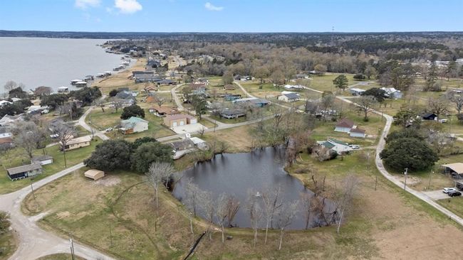 This aerial photo showcases a lakeside community. A small pond is visible in the foreground, adding to the scenic landscape. The area offers proximity to the lake, providing potential for waterfront activities and a peaceful residential setting. | Image 42