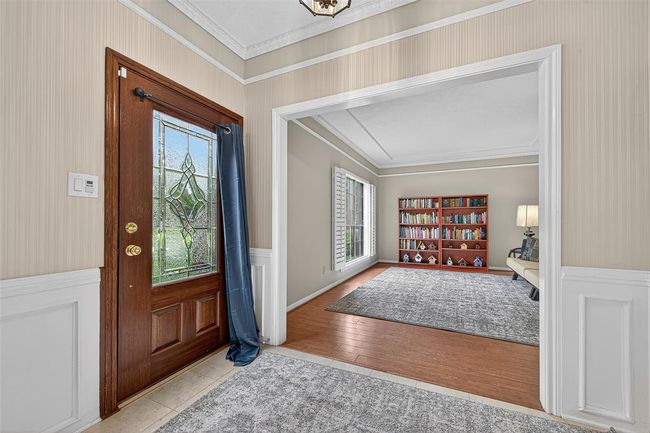 Just inside, the formal living area greets you with rich wood floors, crown molding, and a large sunlit window. An ideal space for quiet conversations or afternoon reading. | Image 8