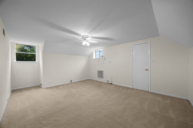 Bonus room with ceiling fan, vaulted ceiling, light colored carpet, baseboards, and a textured ceiling | Image 25
