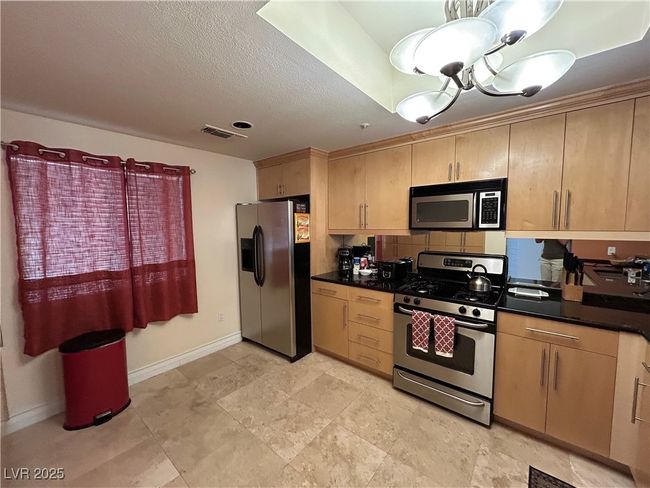 Kitchen featuring appliances with stainless steel finishes, dark countertops, and light brown cabinets | Image 26