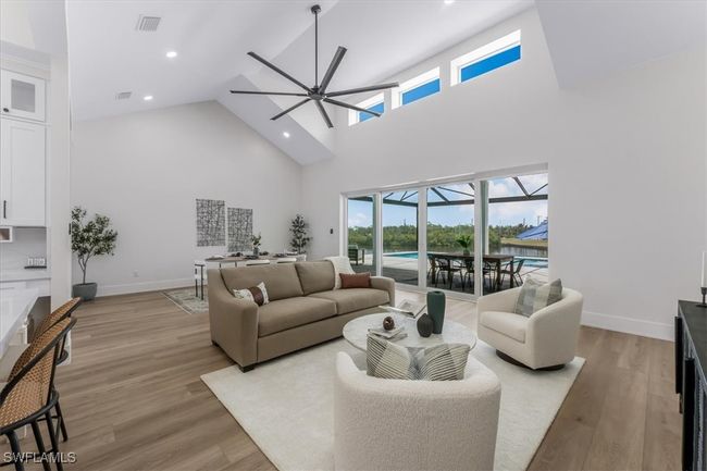 Living room featuring a ceiling fan, high vaulted ceiling, plenty of natural light, light wood-style floors, and recessed lighting | Image 25