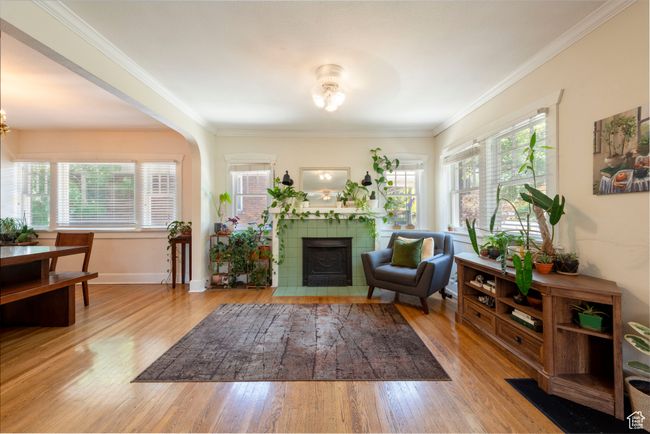 Living room with a tile fireplace, wood finished floors, crown molding, and a chandelier | Image 6