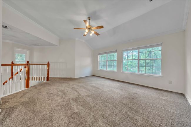 Carpeted spare room featuring a ceiling fan, ornamental molding, and lofted ceiling | Image 23