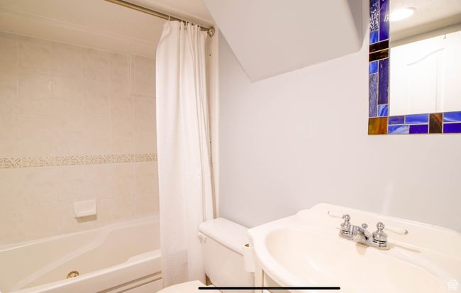Bathroom featuring toilet, a sink, and shower / bath combination with curtain | Image 11
