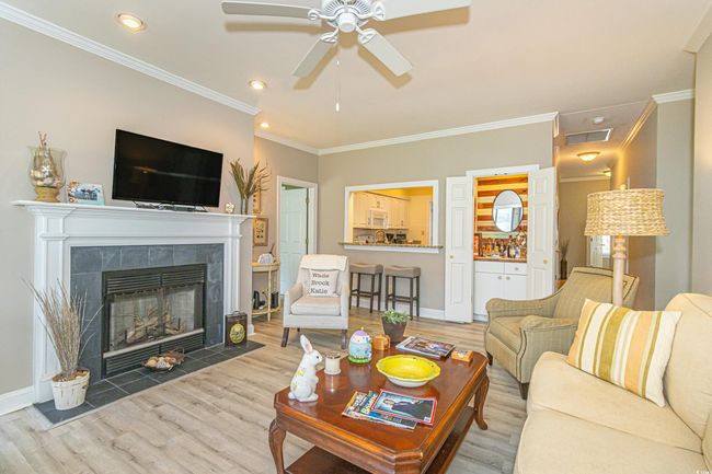 Living room featuring crown molding, baseboards, ceiling fan, a fireplace, and wood finished floors | Image 4