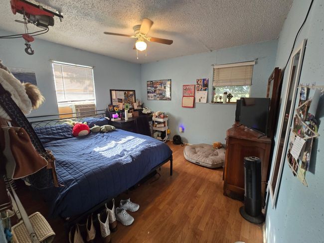 Bedroom with wood finished floors, a textured ceiling, multiple windows, and a ceiling fan | Image 22