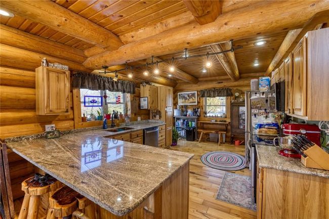Kitchen featuring dishwasher, light wood-type flooring, wooden ceiling, log walls, and a sink | Image 16