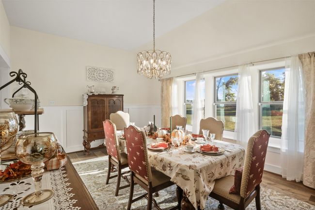 Dining area featuring light wood finished floors, a chandelier, and a wainscoted wall | Image 15