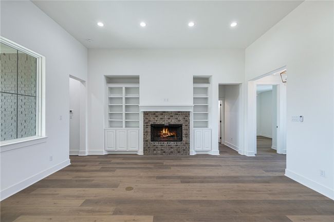 Unfurnished living room featuring dark wood-type flooring, built in features, and a brick fireplace | Image 7