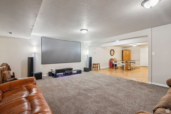 Carpeted home theater room featuring baseboards, a textured ceiling, and visible vents | Image 42