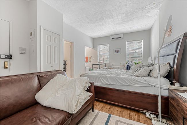 Bedroom with a wall mounted air conditioner, a textured ceiling, and light wood-style flooring | Image 20