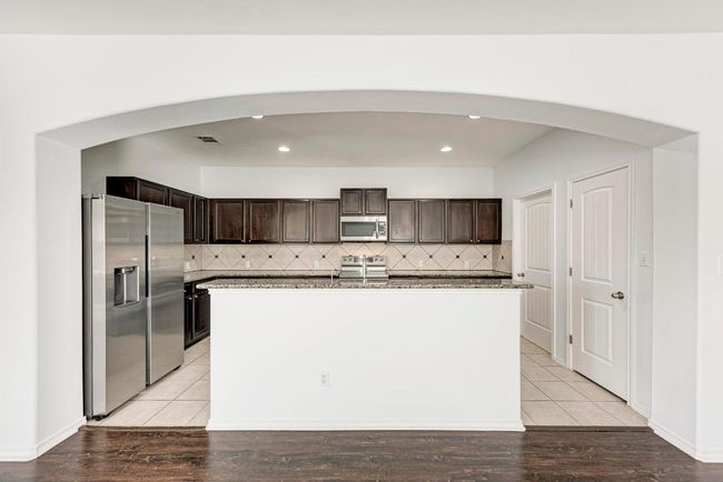Kitchen featuring appliances with stainless steel finishes, arched walkways, dark brown cabinets, and recessed lighting | Image 16