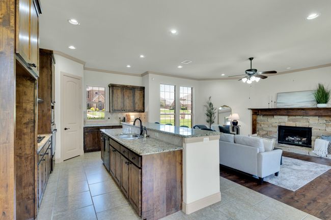 Kitchen with light tile patterned floors, a ceiling fan, a stone fireplace, crown molding, and recessed lighting | Image 11