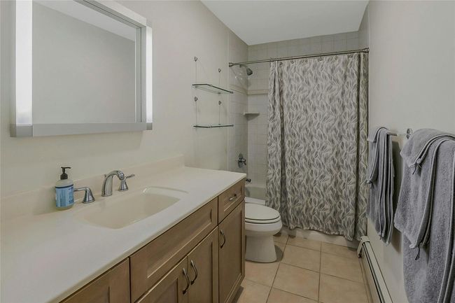 Bathroom with vanity, toilet, a baseboard radiator, tile patterned floors, and shower / tub combo | Image 7