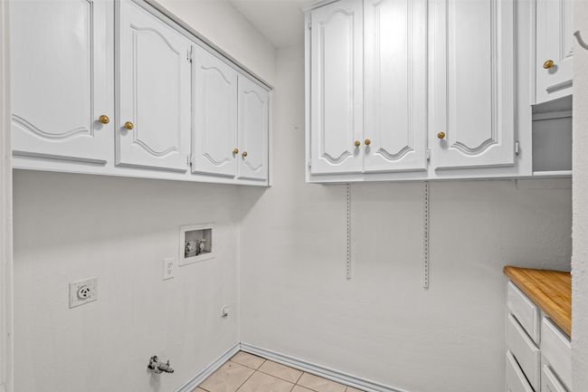 Laundry room featuring cabinet space, gas dryer hookup, washer hookup, light tile patterned floors, and electric dryer hookup | Image 33