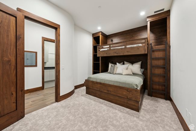Bedroom featuring baseboards, recessed lighting, light carpet, light wood finished floors, and electric panel | Image 95