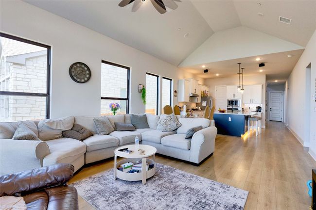 Living room with high vaulted ceiling, a ceiling fan, visible vents, recessed lighting, and light wood finished floors | Image 23
