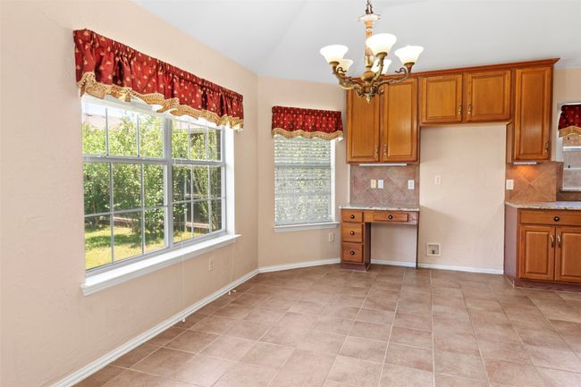 Kitchen with a chandelier, backsplash, healthy amount of natural light, brown cabinetry, and vaulted ceiling | Image 31