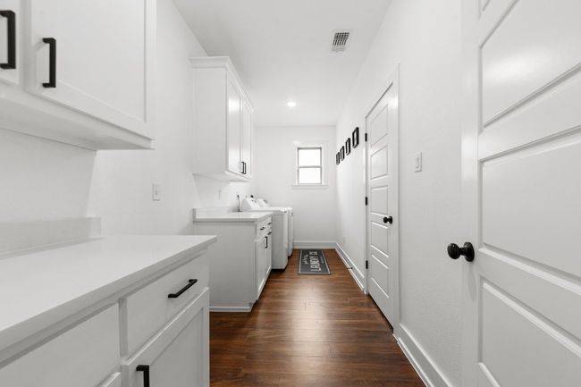 Laundry room featuring dark wood finished floors, recessed lighting, washing machine and clothes dryer, baseboards, and cabinet space | Image 4