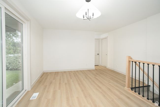 Spare room with healthy amount of natural light, light wood finished floors, a chandelier, and baseboards | Image 15