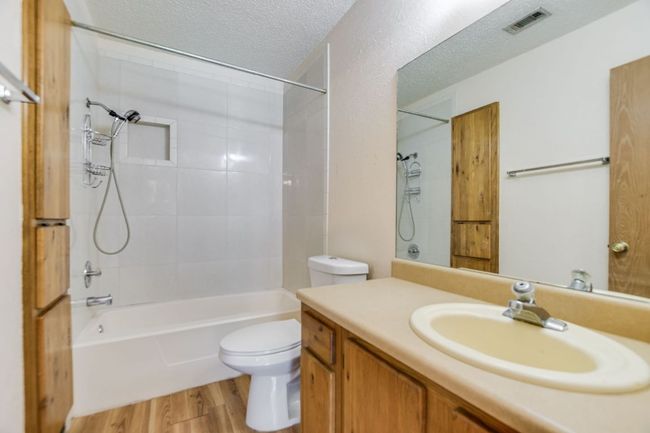 Bathroom with toilet, vanity, wood finished floors, shower / bathtub combination, and a textured ceiling | Image 15