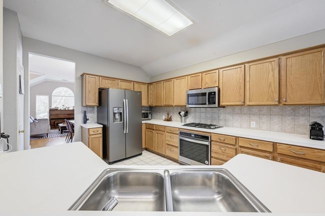 Kitchen with recent appliances with stainless steel finishes, vaulted ceiling, light countertops, tasteful backsplash, and a sink | Image 11