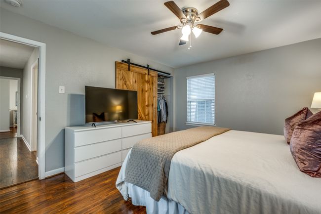 Bedroom featuring dark wood-style floors, a barn door, ceiling fan, and a closet | Image 29