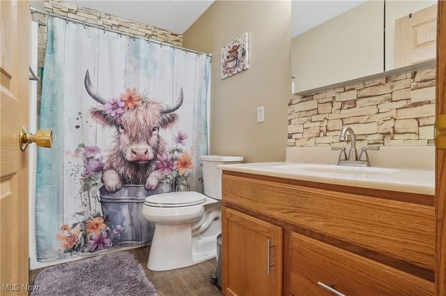 Bathroom featuring toilet, vanity, a shower with curtain, and wood finished floors | Image 34