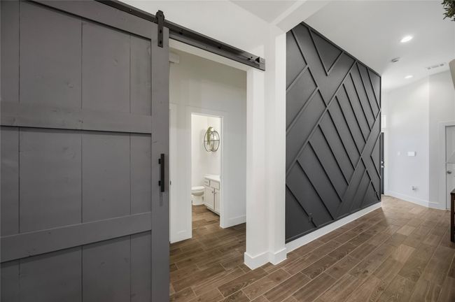 The hallway to the secondary bedrooms is separated by a custom sliding barn door, adding an unexpected designer touch while maintaining the home’s cohesive flow. | Image 22