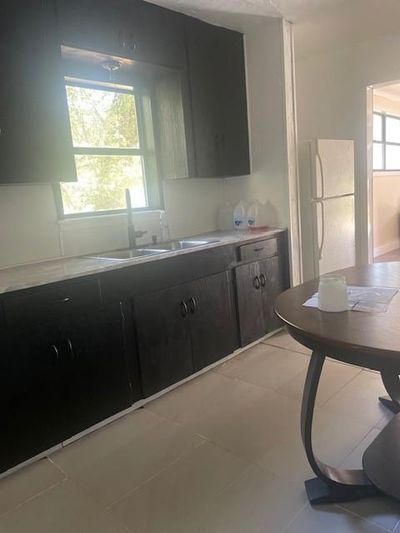 Kitchen with light tile patterned floors, sink, plenty of natural light, and white fridge | Image 3