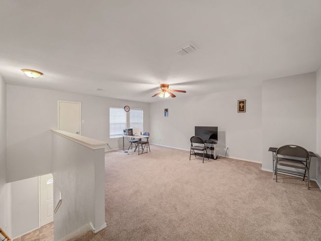 Sitting room featuring light colored carpet, a ceiling fan, baseboards, and an upstairs landing | Image 19