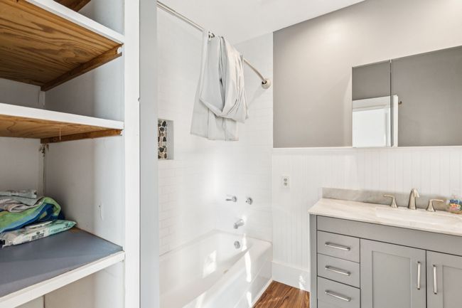 Full bath featuring shower / tub combination, wood finished floors, vanity, and wainscoting | Image 11